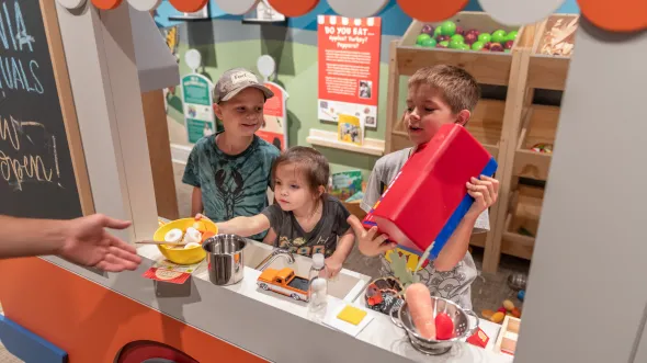 Three children play with toy food in a food truck interactive exhibition