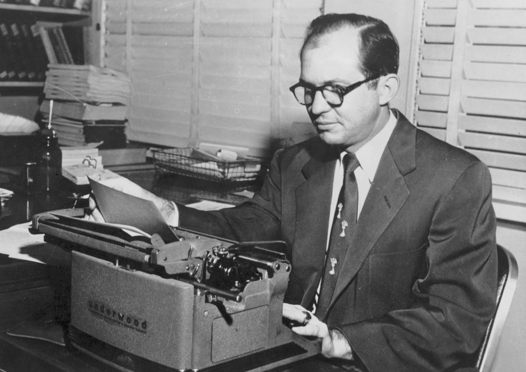 Black and white photograph of James Jackson Kilpatrick working at his desk with a typewriter