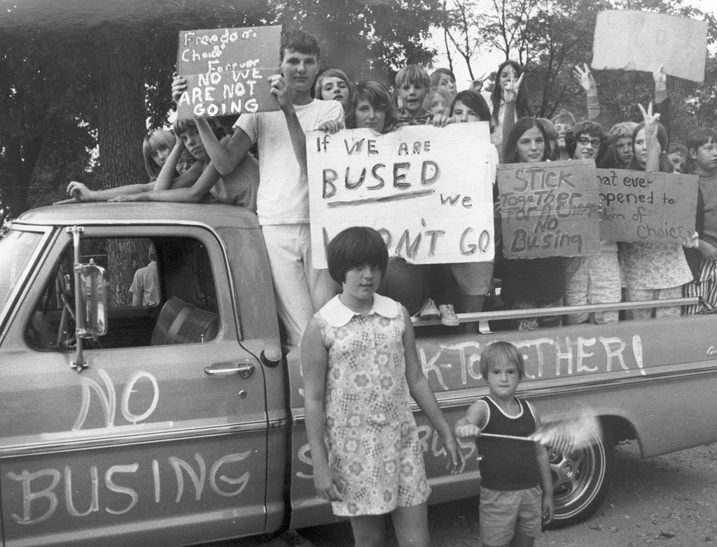 Young students posing in the back of a truck holding signs to protest busing plans saying, “Freedom of Choice Forever, No We Are Not Going”, “If We Are Bused We Won't Go.” 