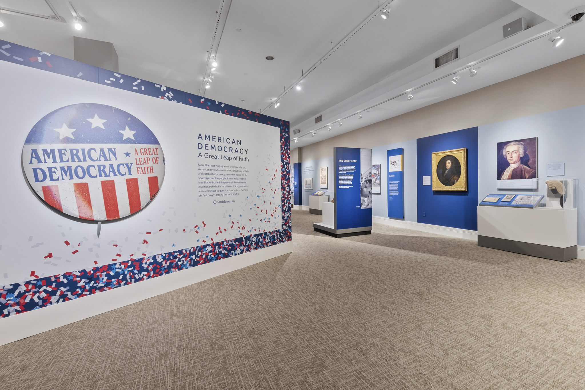 The entrance to a gallery with a wall graphic logo of a political button with American flag design and words American Democracy