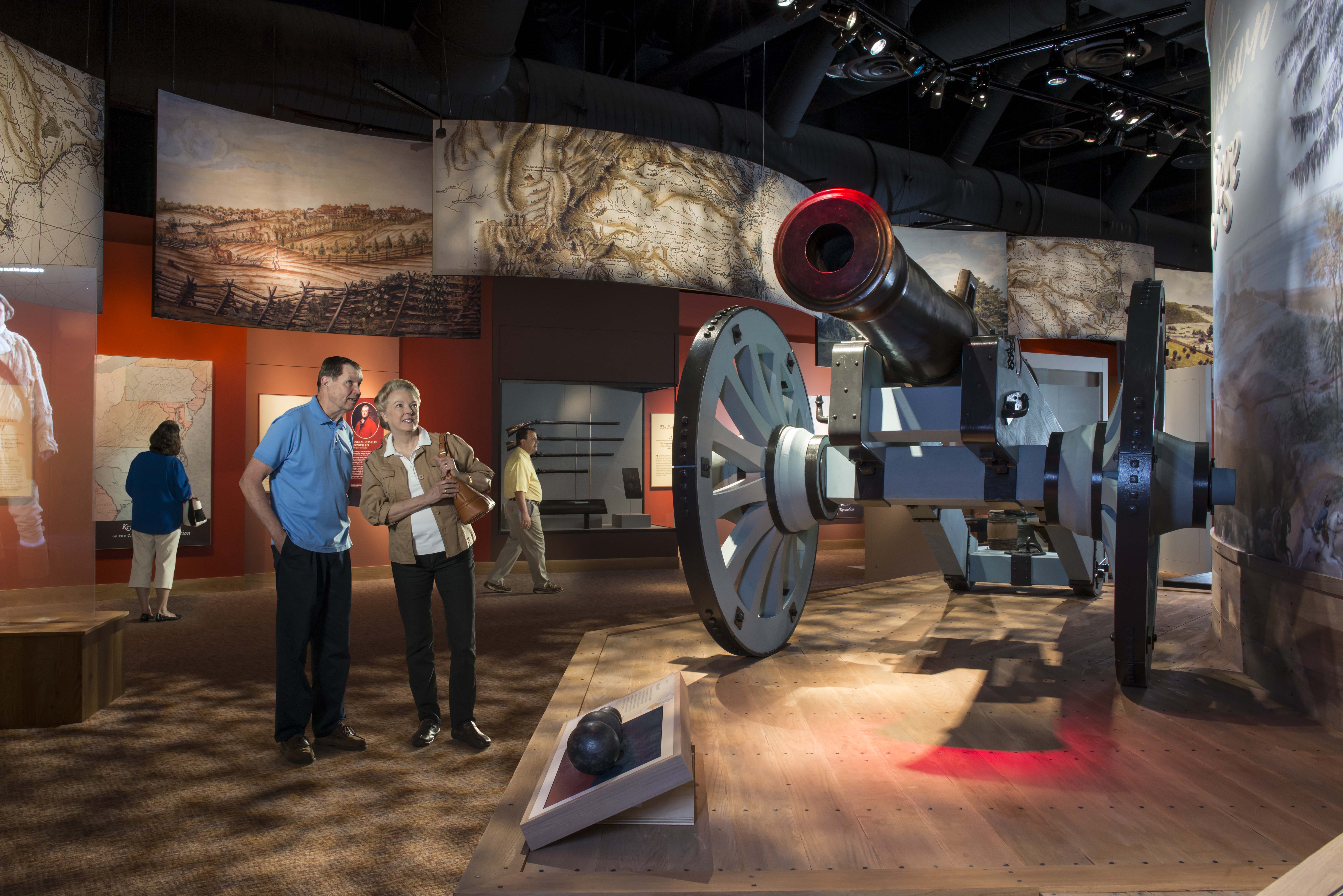 American Revolution Museum at Yorktown_- Two adults looking at a siege cannon in exhibit galleries