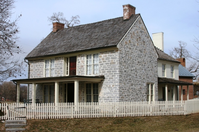 A stone two story house with additions off the back and a covered front porch.