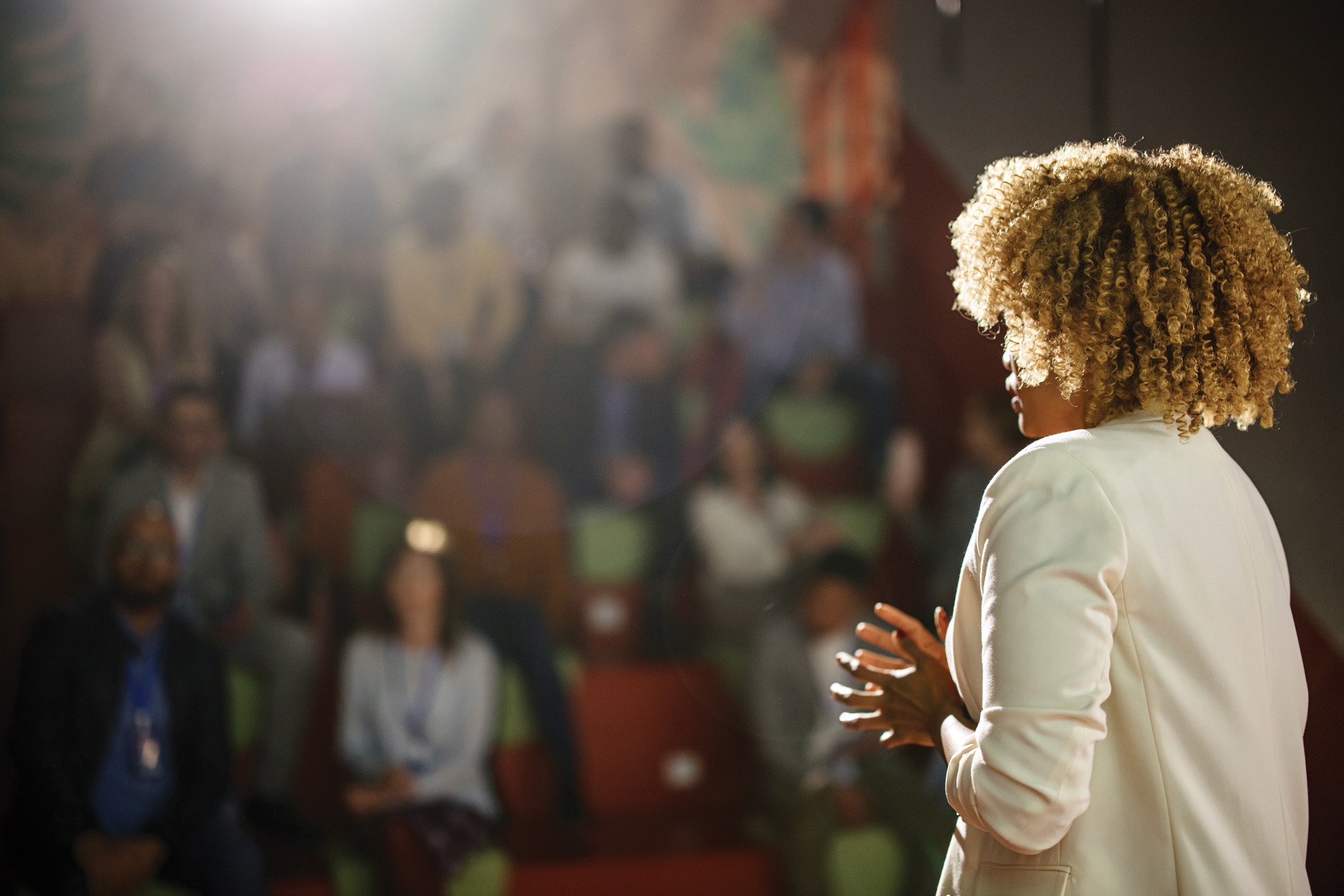 A woman on stage speaking to an audience 