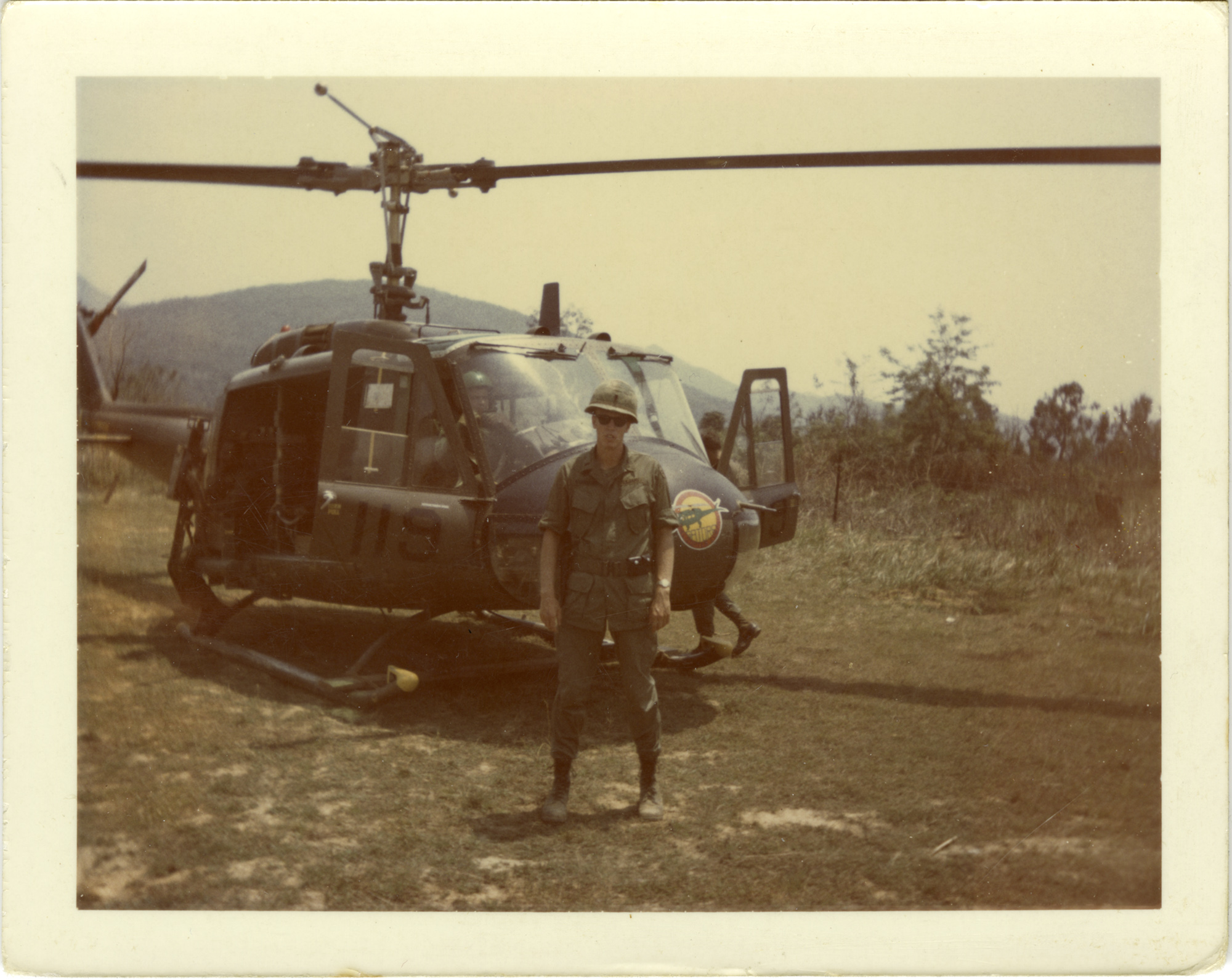 A soldier stands in front of a helicopter