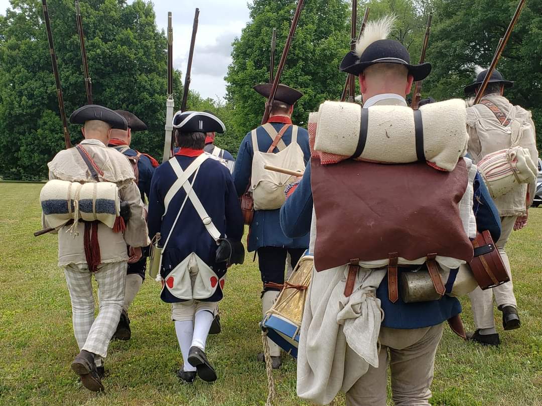 Revolutionary war soldier reenactors in uniforms carrying muskets