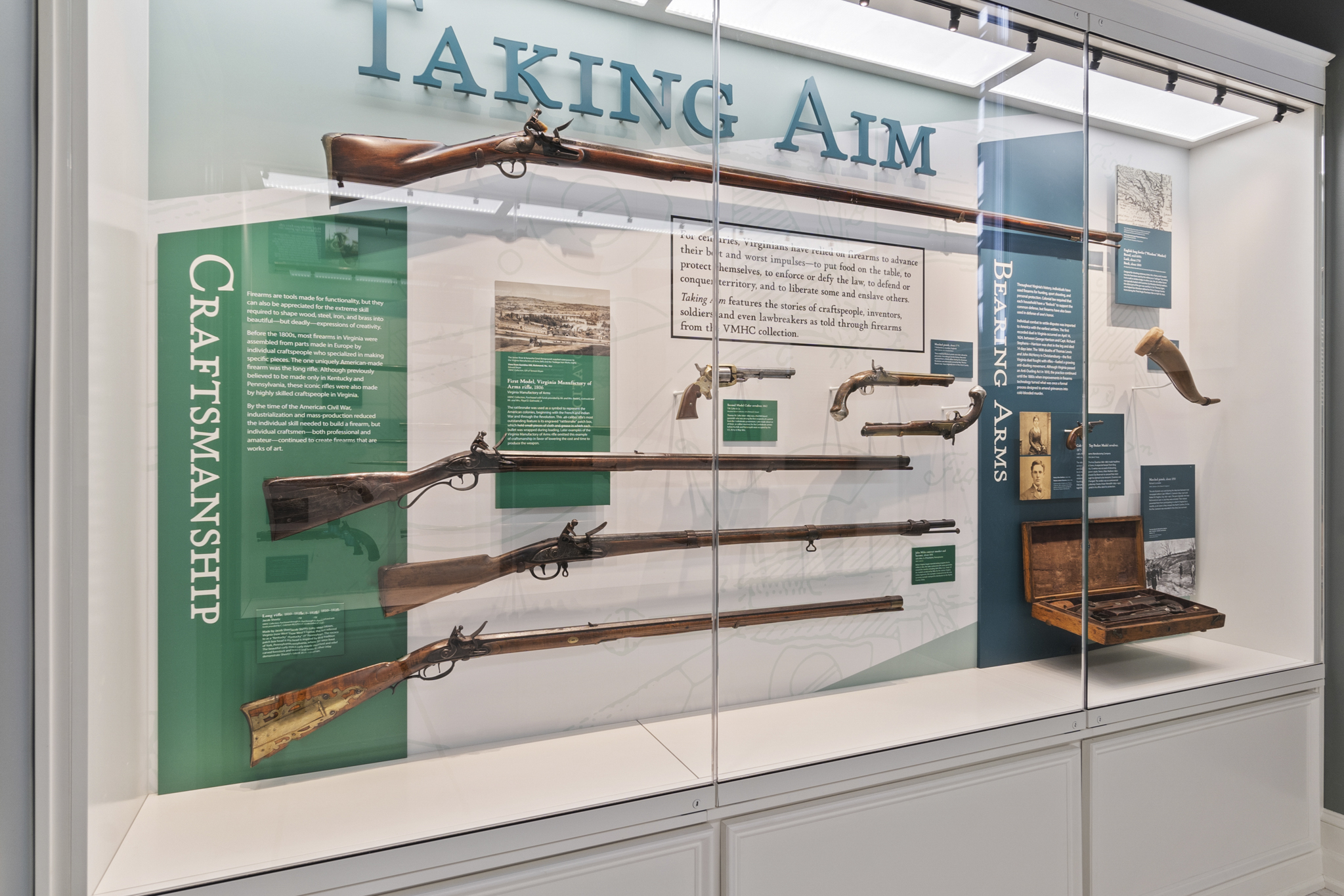 A display case with historical guns and the exhibition title Taking Aim