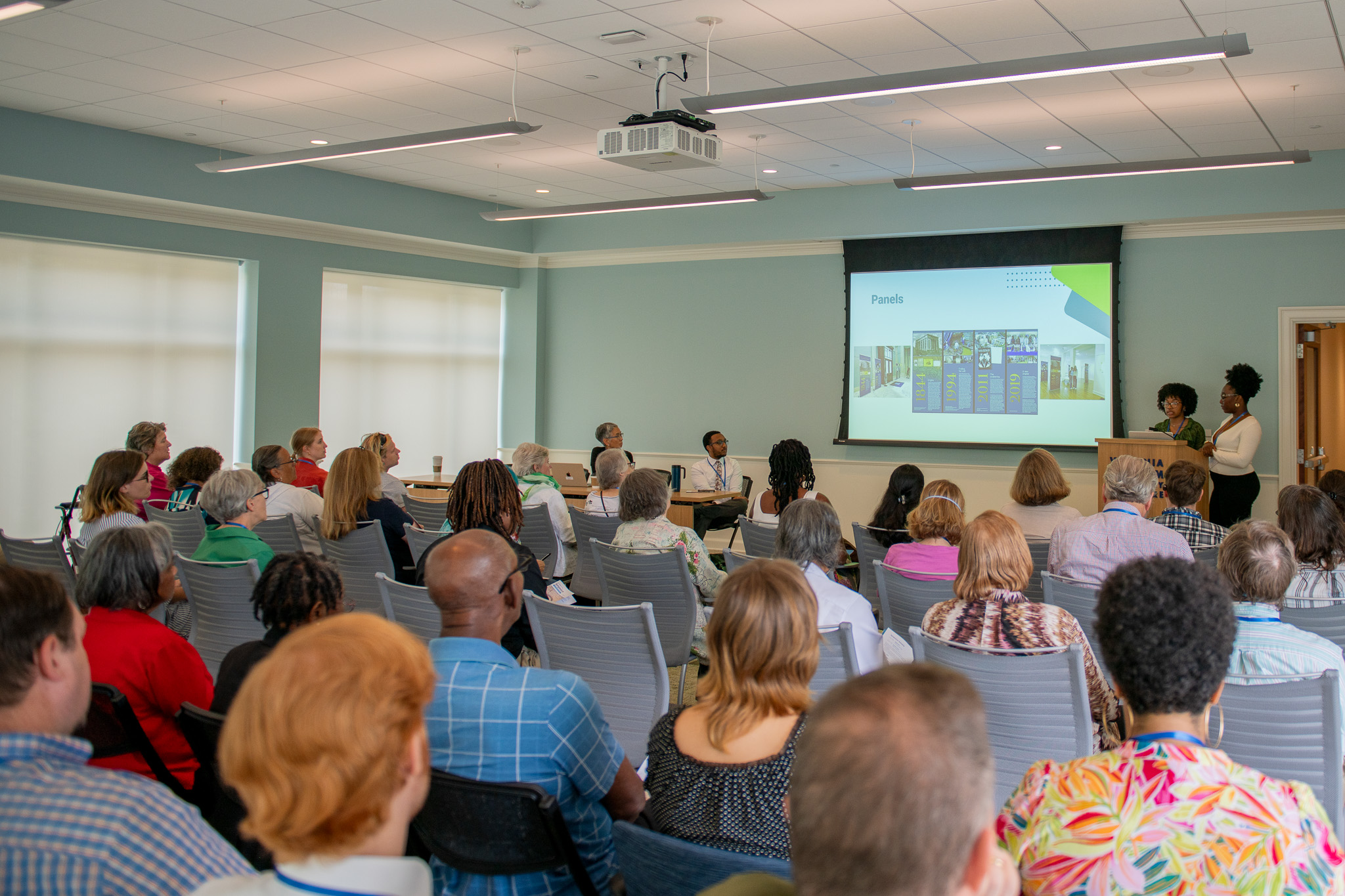 Two speakers present to an audience at the VMHC
