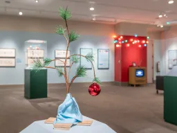 Merry Christmas, Charlie Brown Exhibition installed in the gallery with small tree with red ornament in foreground