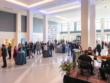 People gather around tables and listen to a band during a reception in Commonwealth Hall 