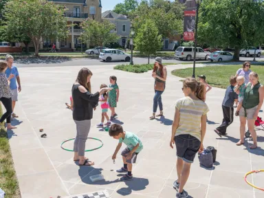 A color photograph of children playing on the VMHC front lawn.