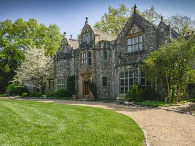 A historic Tudor mansion with a gravel drive and grassy lawn