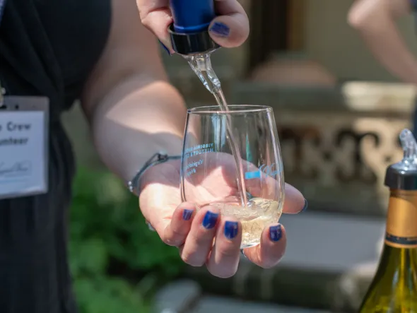A hand pouring wine into a glass