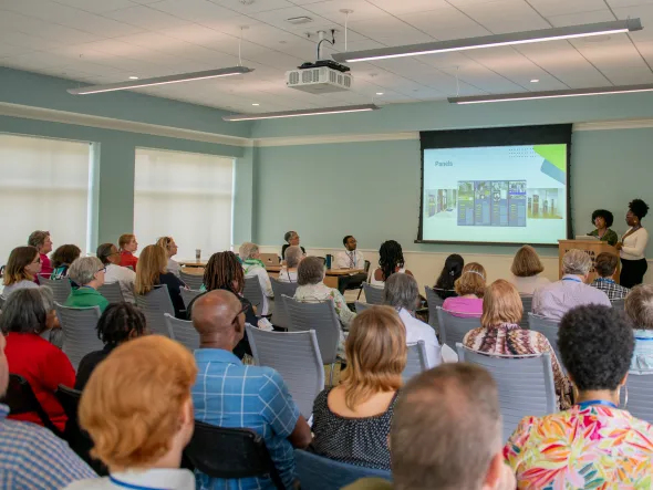 A classroom full of people watch a powerpoint presentation.