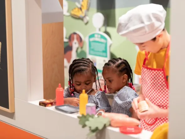 Three children play with toy food in a food truck interactive exhibition