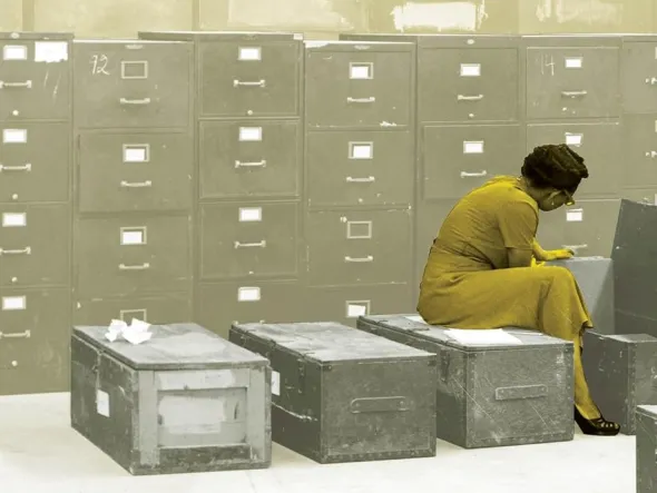 Proximity to Power: Rethinking Race and Place in Alexandria, Virginia A woman in a yellow dress sits on a metal box in front of a wall of filing cabinets, writing or reviewing papers. The background is tinted in muted sepia tones, emphasizing the archival or historical setting.