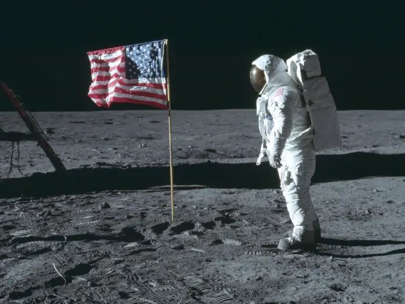 An astronaut in a space suit on the surface of the moon with an American flag