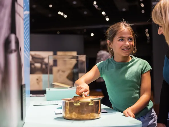 A child plays with cooking tools in an exhibition display.
