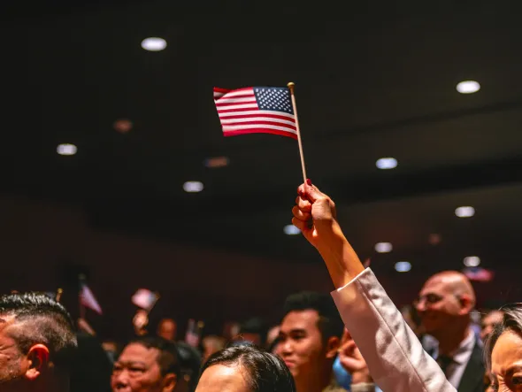 A person holds up a miniature American flag in a crowded auditorium.