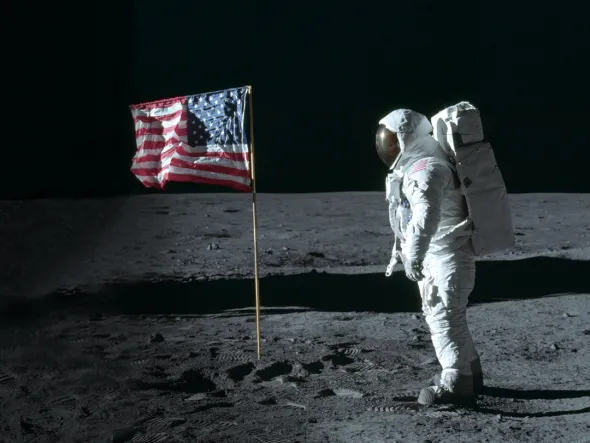 An astronaut in a space suit on the surface of the moon with an American flag