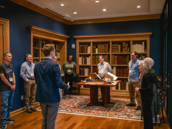 Man leads a discussion to a group in a private library room. 