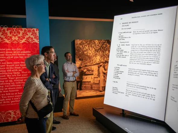 People view a large illuminated cookbook model in a gallery.