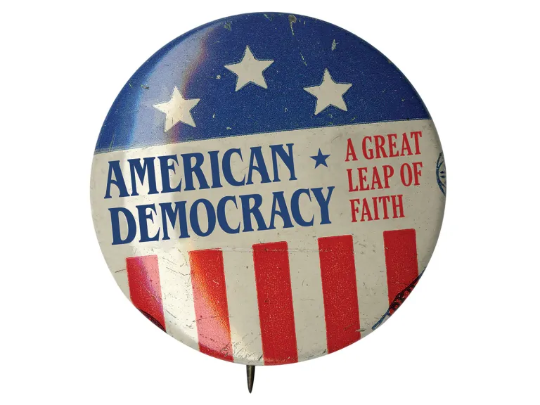A pin-back button with American flag stars and stripes and the words: American Democracy - A Leap of Faith