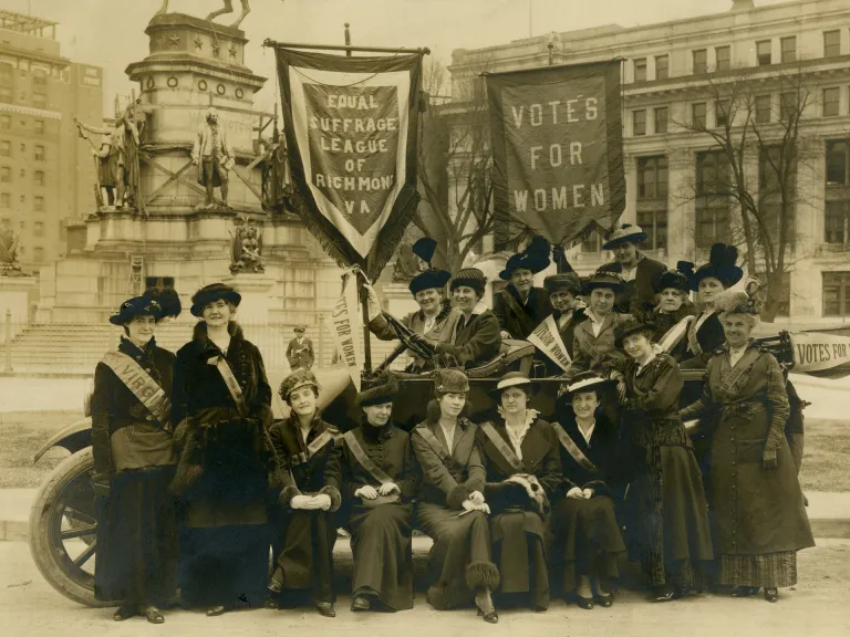 Black and white photograph of women gathered in Capitol Square holding large banners which read "Equal Suffrage League and Richmond, Virginia" and "Votes for Women." Many otes for Women." 