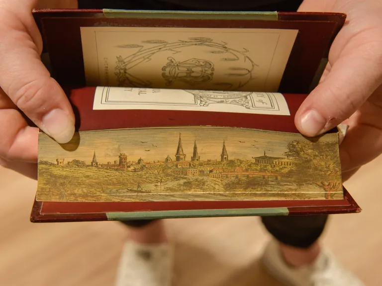 Pages ruffled farther apart show a painted landscape and city
