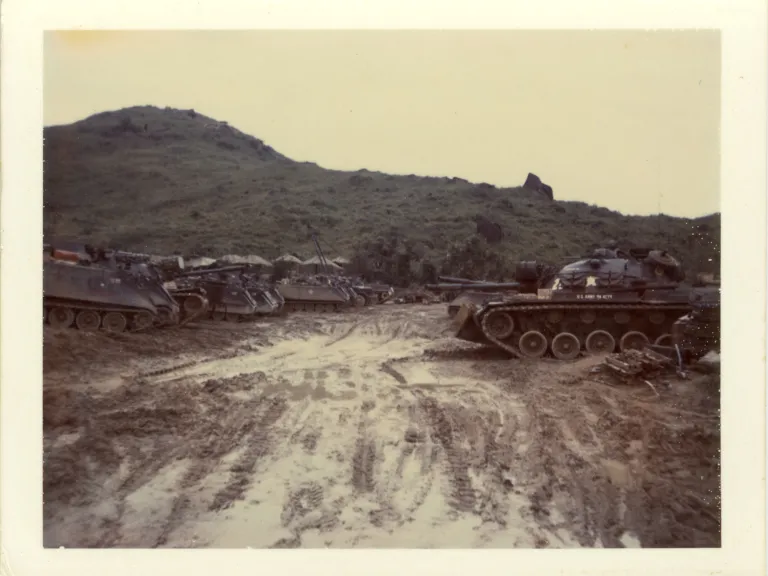 Muddy clearing filled with military vehicles