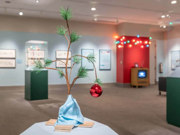 Merry Christmas, Charlie Brown Exhibition Merry Christmas, Charlie Brown Exhibition installed in the gallery with small tree with red ornament in foreground