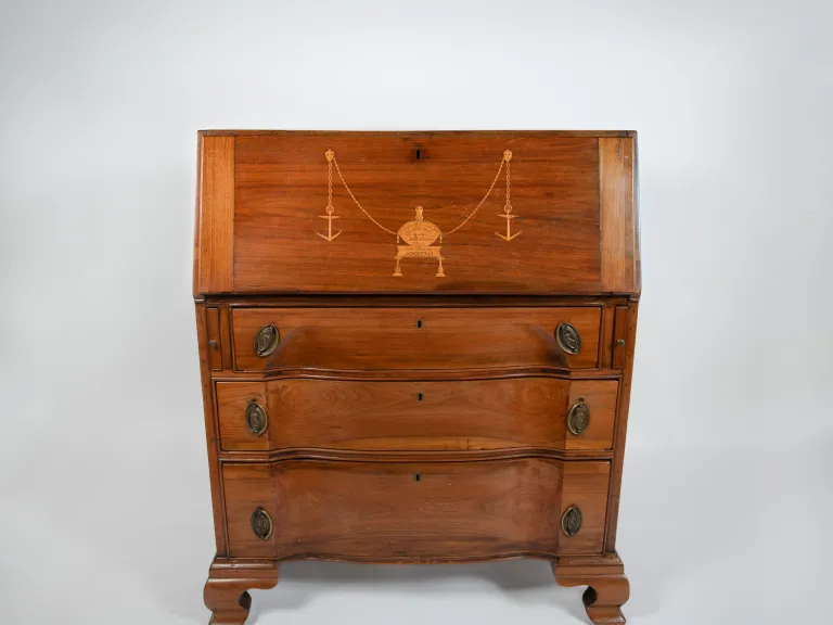 A wood rolltop desk with three drawers and a gold scale symbol embossed on the top