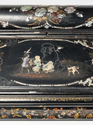 A top-down view of a small black-laquered writing desk with pearl inlaid in a floral motif.