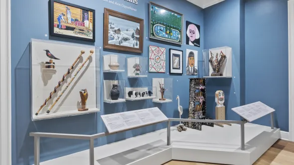 A gallery display with various folk art