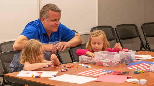 A parent and two children work on a paper craft activity