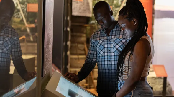 A couple looks at an interactive touch screen in a gallery