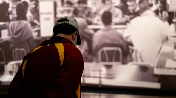 A museum visitor looks at a lunch counter installation and photograph