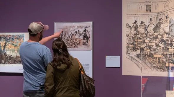 Two guests look at reproductions on a gallery wall
