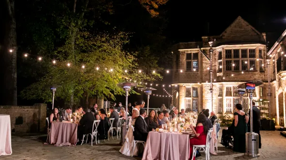 Patio of Virginia House filled with tables and lit with strings of bulb lights with guests enjoying the party