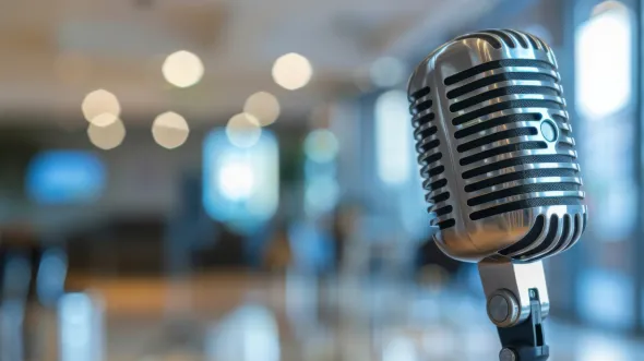 Close-up of a vintage microphone with a softly blurred background in a warm, inviting indoor setting.