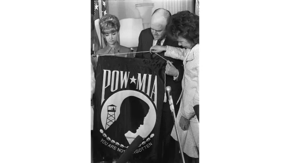 A black and white photograph of the presentation of the POW/MIA Flag