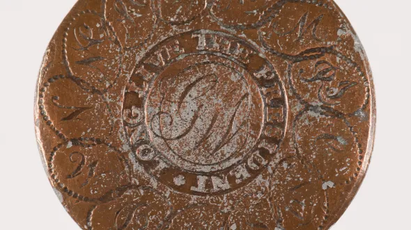 A copper coin with the initials GW in the center and words around it: Long Live the President