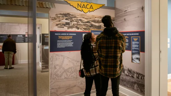 People look at panels about NACA and early space exploration in a gallery