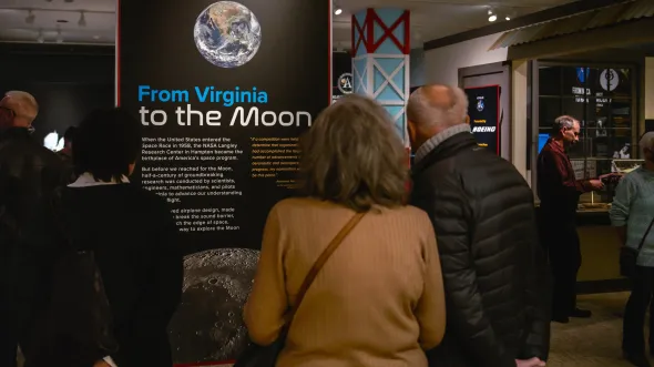 People look at panels about Virginia's contributions to space exploration in a gallery