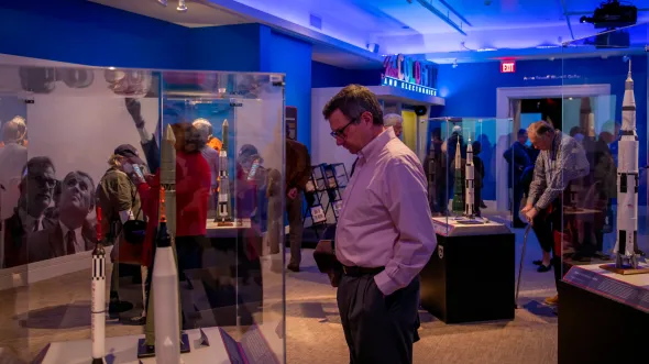 People look at models of rockets and space shuttles in gallery display cases