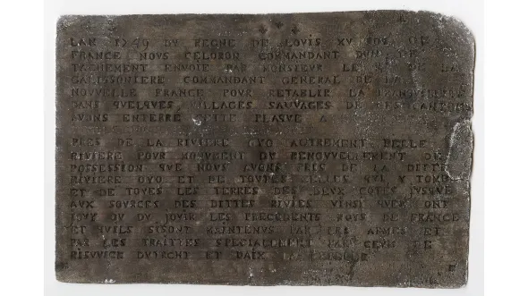 The Celoron Plate, a small greyish brown rectangle with writing engraved into it. 