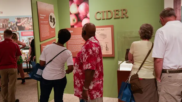 People explore the Cheers, Virginia! exhibition with graphics and artifacts related to beverage history in Virginia