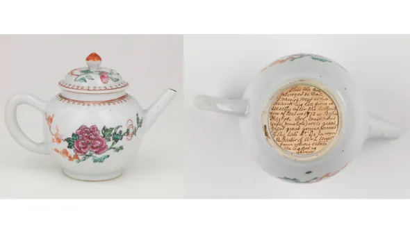 A white teapot with a floral pattern and a handwritten letter adhered to the base.