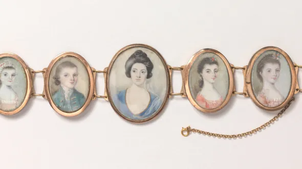 A bracelet consisting of 5 minature portraits of a woman and children framed in gold.