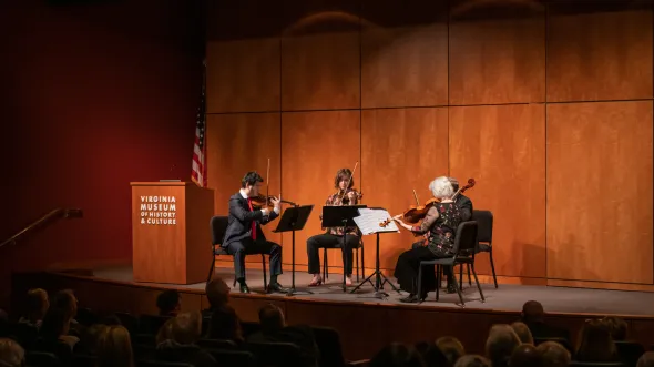 Musicians play on a stage to a packed auditorium.