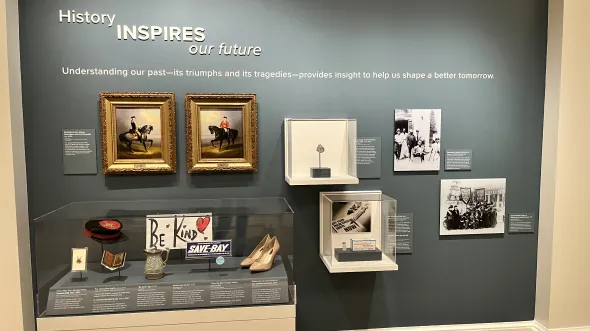 A display of framed paintings, shoes, signs, and other small artifacts related to Virginia history